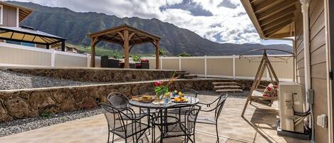 Une terrasse extérieure avec une table et des chaises, une pergola et une vue sur la montagne.