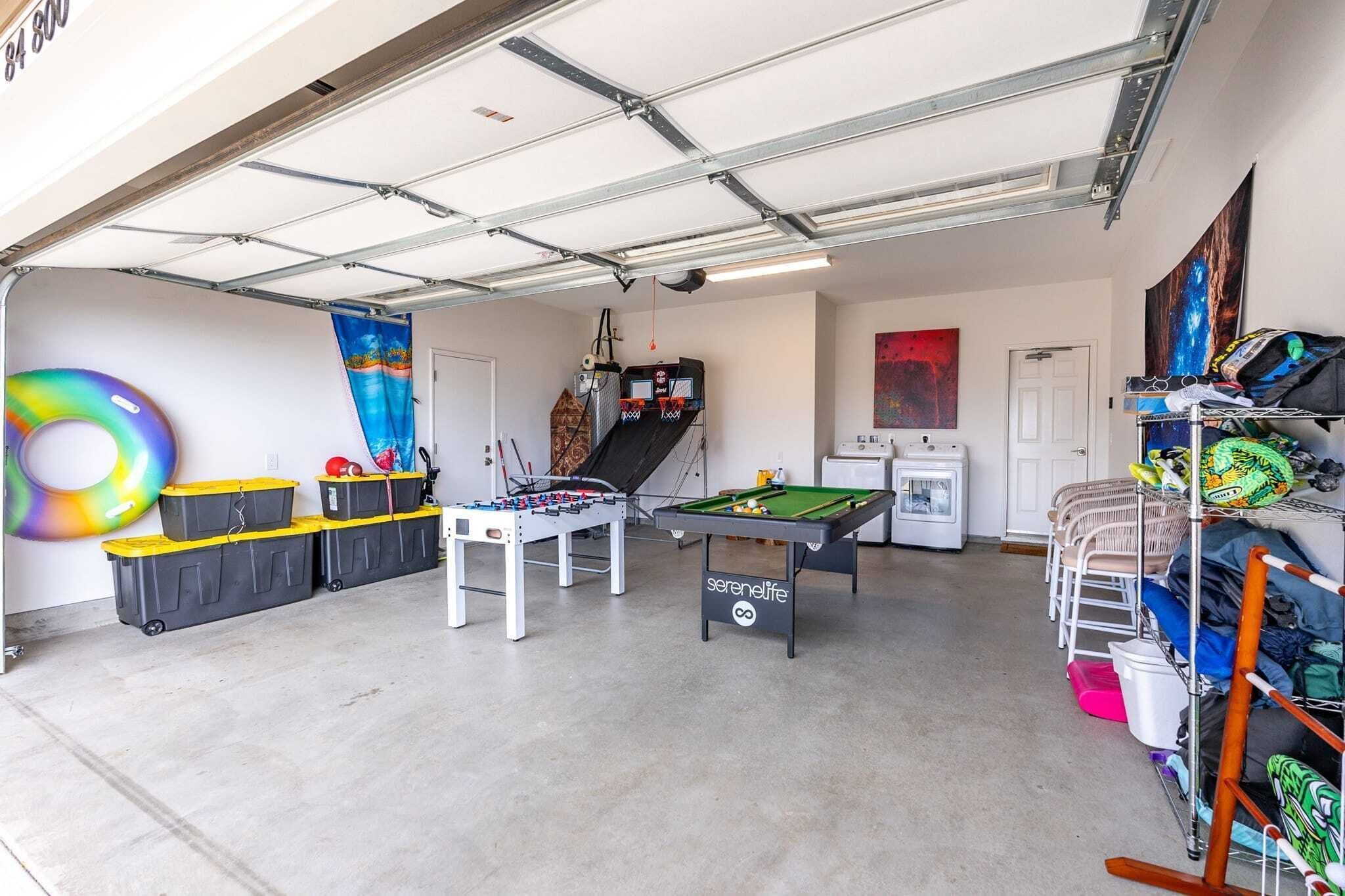 A garage with a pool table, foosball table, and storage bins.