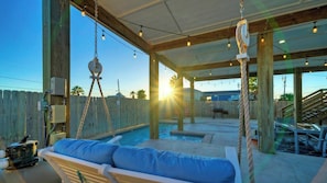 Un'area esterna coperta con piscina, altalena e barbecue.