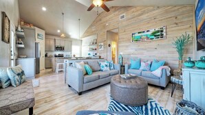 A spacious living area with a grey sofa, ottoman, and a wooden ceiling fan. - Priv Pool, Walk to Marina + Eateries, 3 Mins to Beach Marlin Azul by Avantstay (Port Aransas)