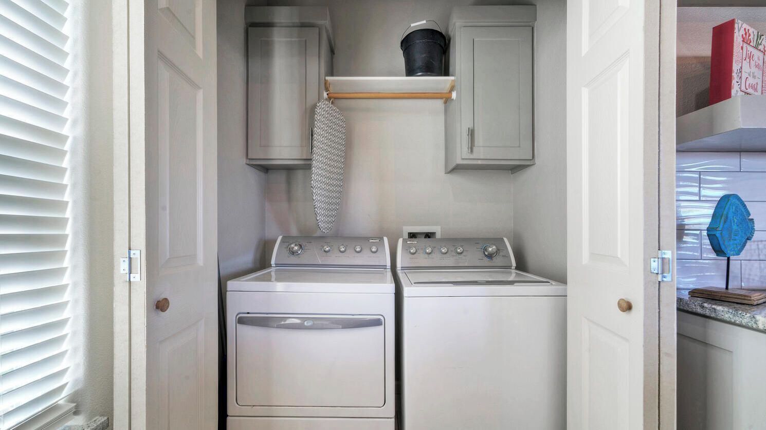 A laundry room with a dryer, washing machine, and a hanging rack.