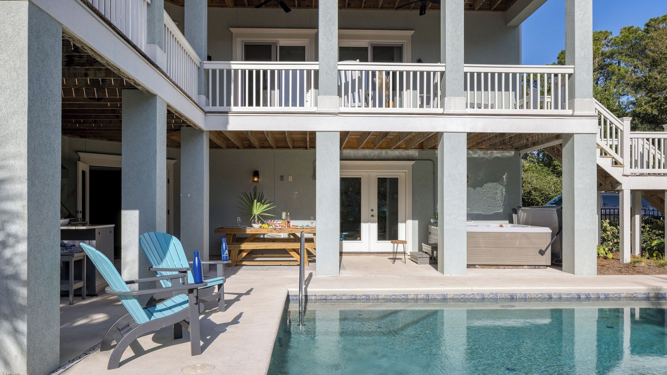 A two-story building with a pool, outdoor seating, and a covered patio area.
