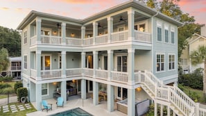 A multi-story house with balconies, a pool, and outdoor seating.