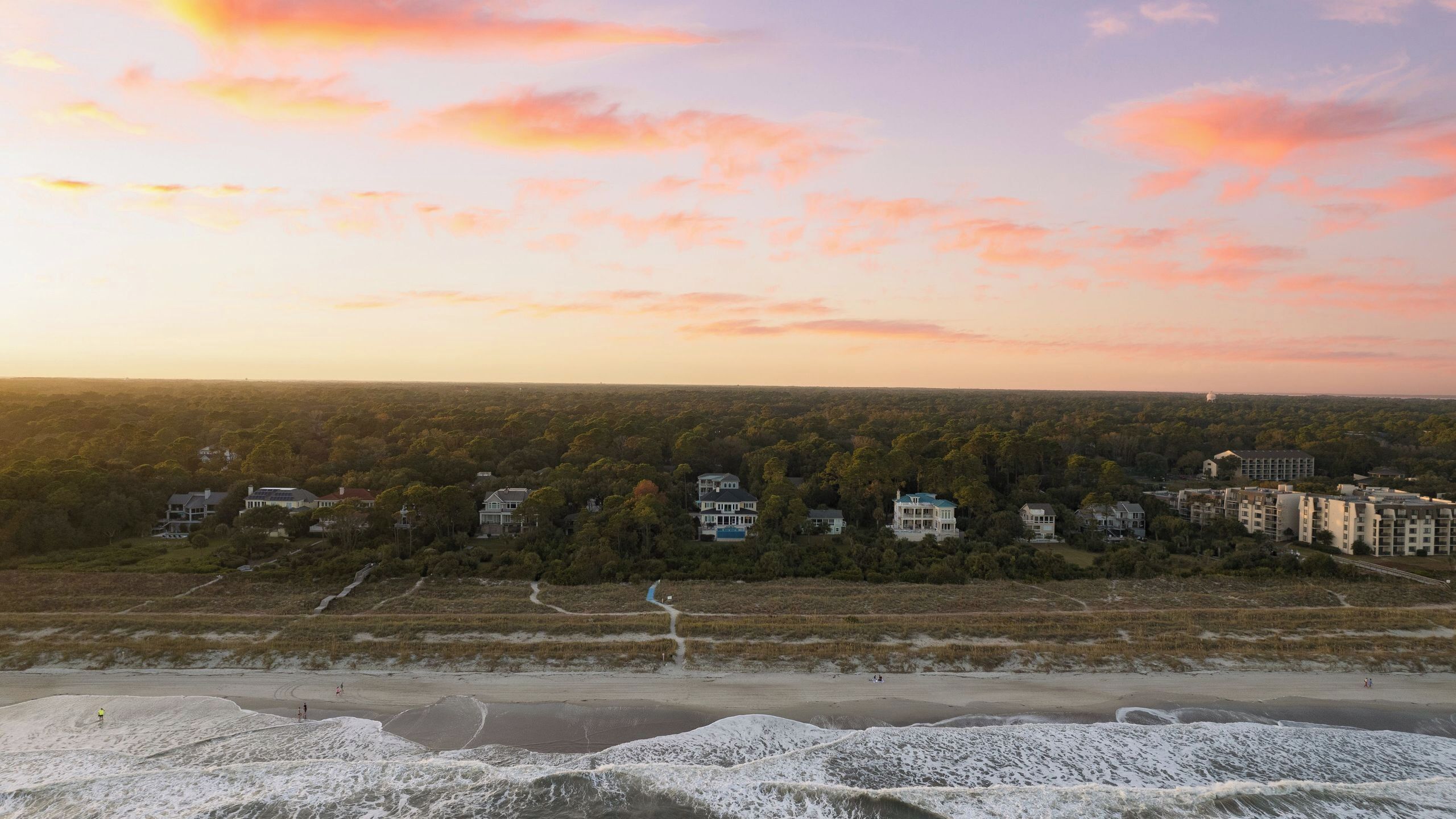 Een kustlandschap met woongebouwen, een strand en een bebost gebied.