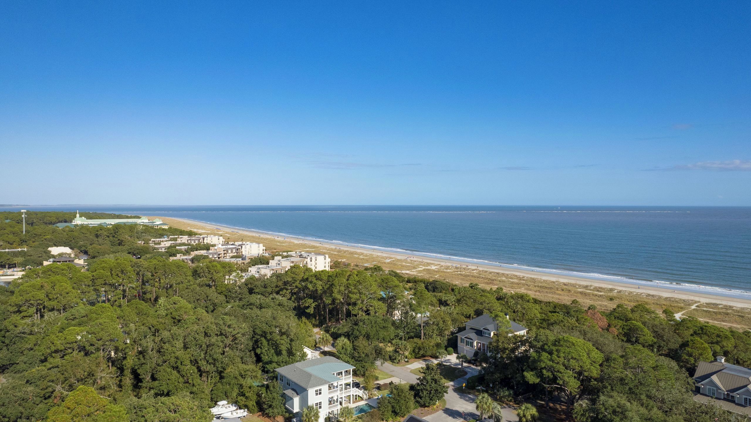 A coastal residential area with houses, a beach, and a clear blue sky.