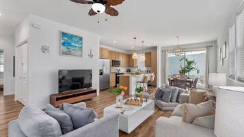 A modern living room with a flat-screen TV, a coffee table with decorative items, and a seating area with sofas.