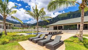 Un complexe hôtelier doté d’une piscine, de chaises longues, de palmiers et offrant une vue sur les montagnes.