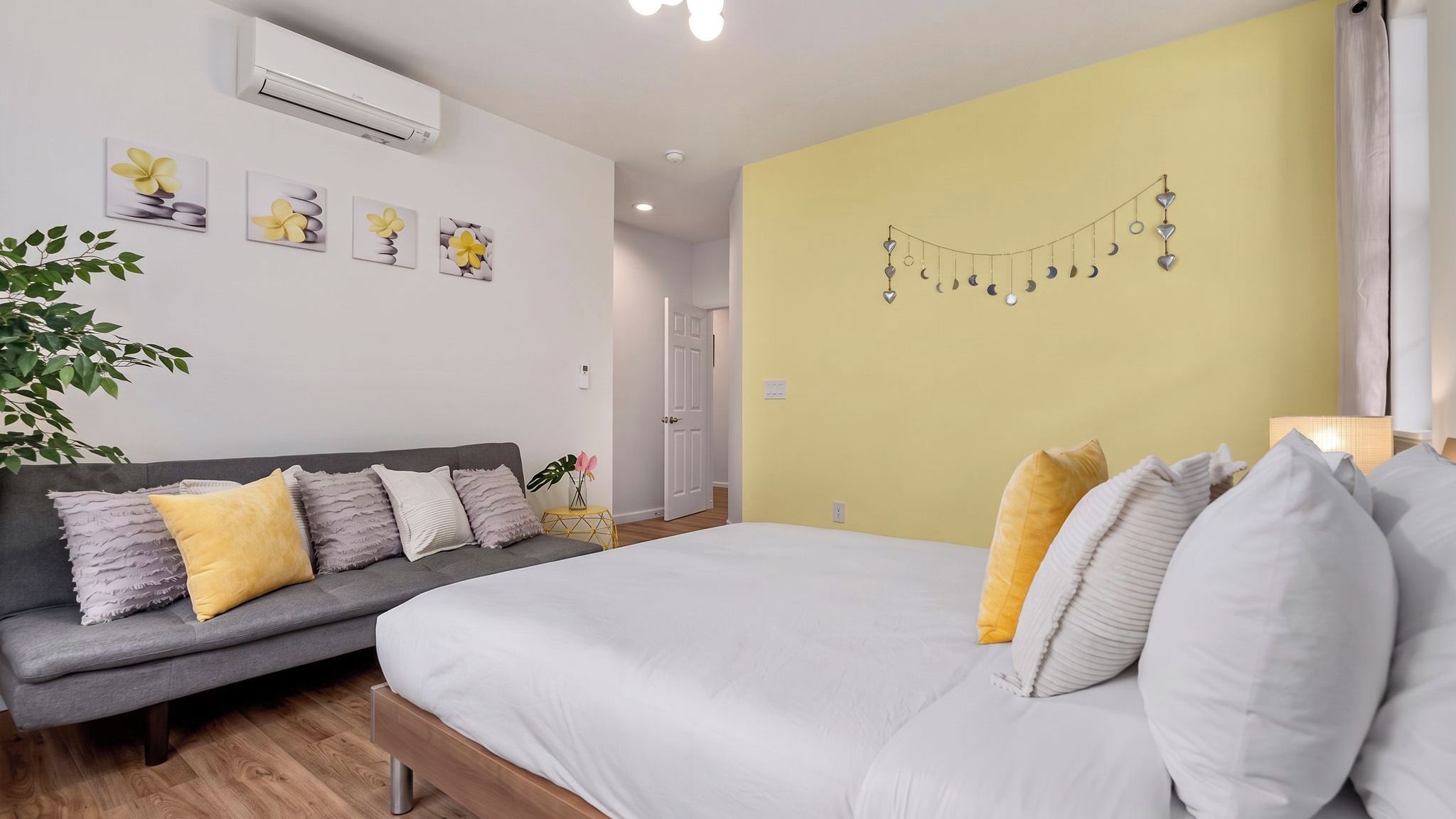A bedroom with a bed, a grey sofa, and a wall with a string of decorative lights.