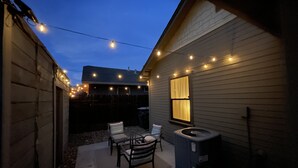 Ein Hinterhof mit einer Terrasse, einem Tisch, Stühlen, einem Whirlpool und Lichterketten.