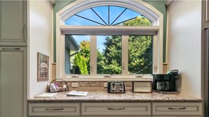 A kitchen with a large window, a countertop, and a coffee maker.