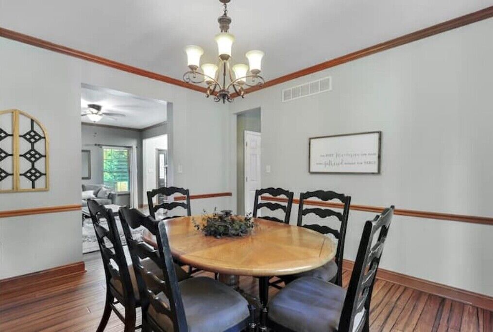 A dining area with a round wooden table, black chairs, and a chandelier.