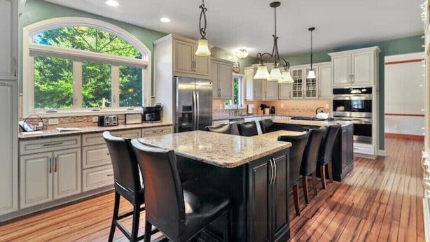 A modern kitchen with a large island, bar stools, and pendant lighting.
