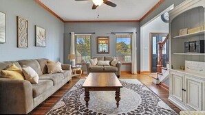 A spacious living room with a ceiling fan, two sofas, a coffee table, and a patterned rug.
