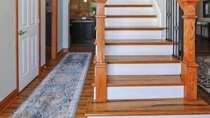 A staircase with wooden balusters and a handrail, leading to an upper floor.