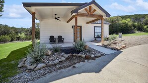 Ein Bungalow mit überdachter Veranda, Deckenventilator und zwei Stühlen davor.