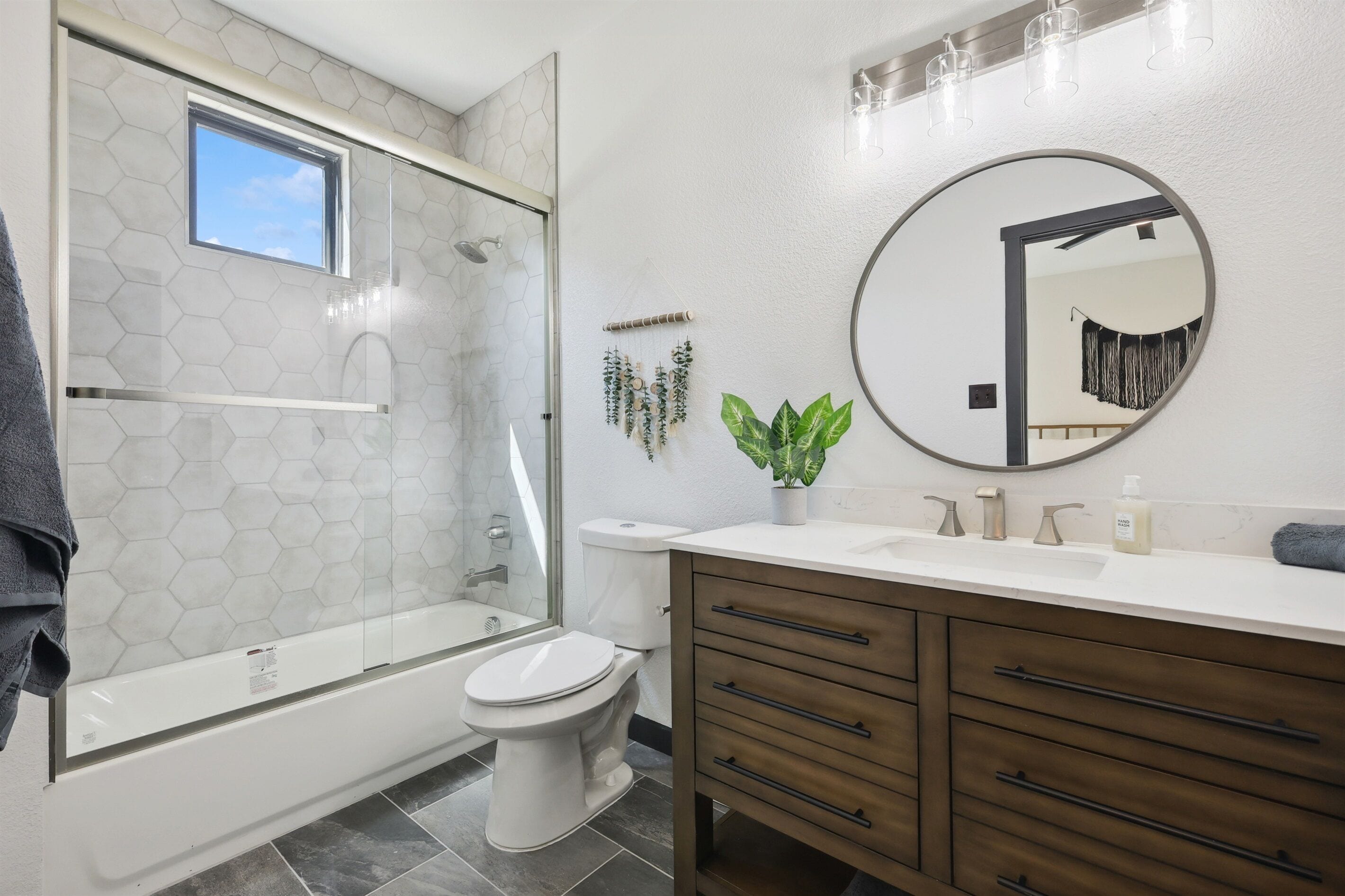 A modern bathroom with a glass-enclosed shower, a toilet, a sink with a mirror, and wooden cabinets.