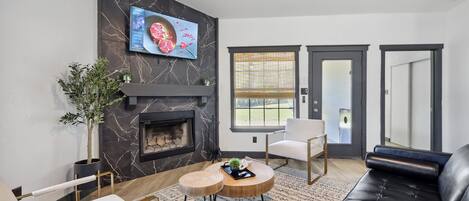 A modern living room with a fireplace, a flat-screen TV, a sofa, and a coffee table.