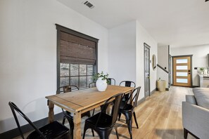 A dining area with a wooden table, black chairs, and a white vase with a plant. - The Retreat 21: Reel Deal (Graford)