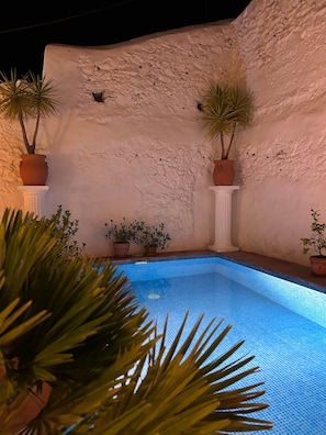 A swimming pool with a textured wall and potted plants. - La Casa Antigua, Canillas de Albaida (Canillas de Albaida)