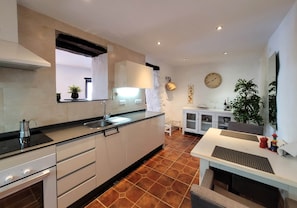 A modern kitchen with a built-in oven, a sink, and a dining area with a table and chairs. - La Casa Antigua, Canillas de Albaida (Canillas de Albaida)