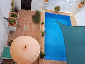 A rooftop pool with a blue tiled floor, surrounded by potted plants and a large umbrella. - La Casa Antigua, Canillas de Albaida (Canillas de Albaida)