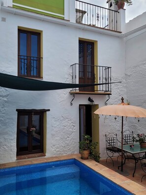 Un immeuble résidentiel doté d’une piscine, de mobilier d’extérieur et d’un patio couvert.