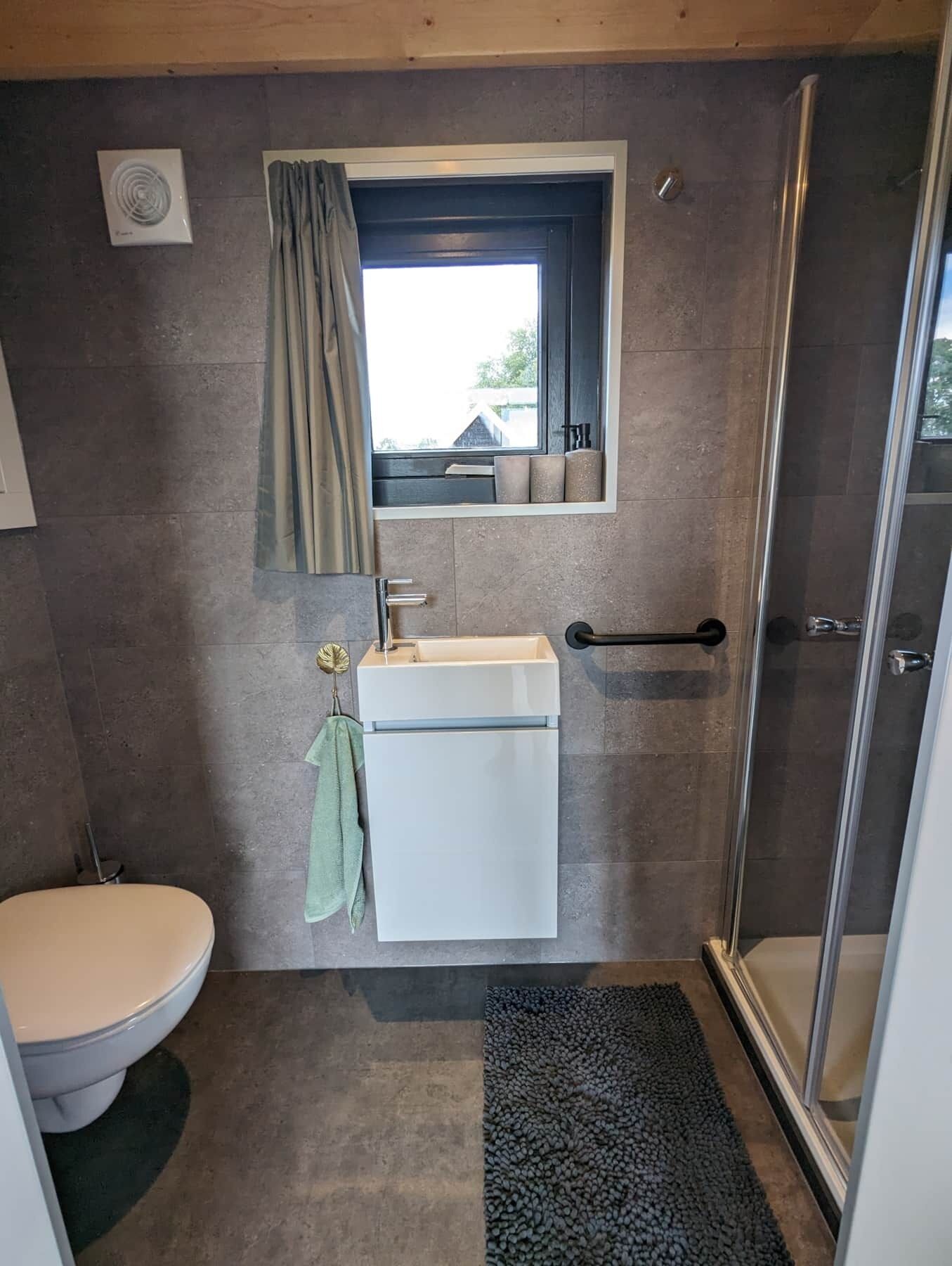 A compact bathroom with a toilet, sink, and shower.