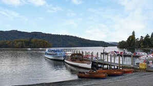 Un lac paisible où des bateaux sont amarrés à un quai, le tout entouré de collines boisées.
