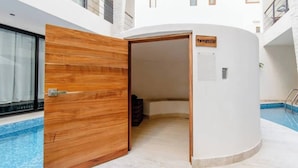 A modern indoor pool area with a wooden door leading to a room labeled "Temazcal." - Kasa Kolibri 2 bedroom apartment in Aldea Zama close to beach (Tulum Quintana Roo)