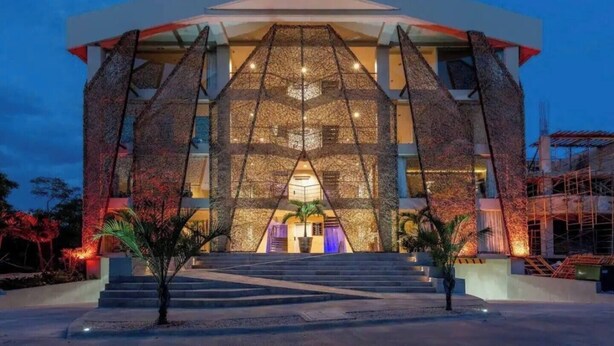 A modern building with a geometric facade, large windows, and a central entrance with steps. - Kasa Kolibri 2 bedroom apartment in Aldea Zama close to beach (Tulum Quintana Roo)