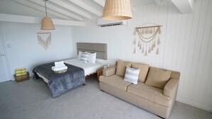 A hotel room with a bed, a sofa, a hanging light, and a wall-mounted air conditioner. - Villa Picuas MR in Rio Grande Magical place (Río Grande)