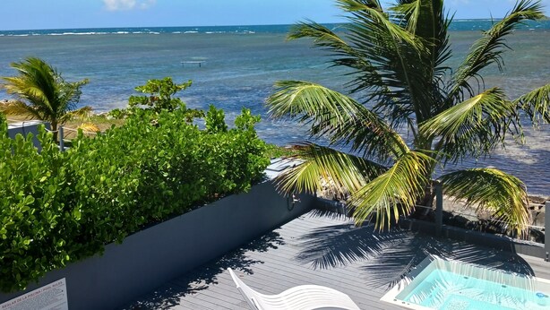 A wooden deck with a pool, palm trees, and a view of the ocean. - Villa Picuas MR in Rio Grande Magical place (Río Grande)