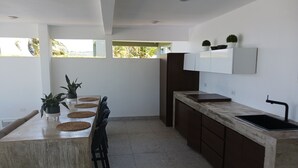 A modern kitchen with a central island, dark cabinetry, and a large window providing natural light. - Villa Picuas MR in Rio Grande Magical place (Río Grande)