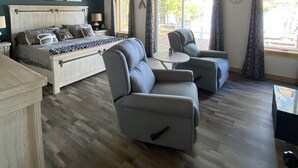 A spacious bedroom with a large bed, a ceiling fan, and a view of the outdoors through large windows. - Anna Bananas Beachfront Bungalow (Hazelhurst)