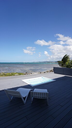A wooden deck with two white lounge chairs facing a pool and ocean view. - Villa Picuas L in Rio Grande Magical place (Río Grande)