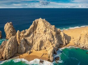 A coastal landscape with rocky formations and a sandy beach. - Water condo w/ private terrace & best LOCATION in Los Cabos Marina Downtown... (Cabo San Lucas)