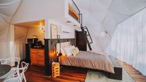 A tented accommodation with a bed, a desk, a chair, and a small table. - Mockingbird Geodesic Dome at Starlight Haven Resort (Hot Springs)