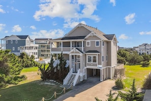 A multi-story residential building with a prominent front porch and a staircase leading to the entrance.