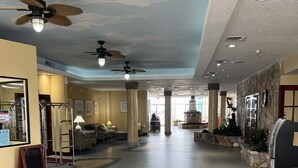 Un vestíbulo amplio con techo alto, ventiladores de techo y un diseño de suelo circular con mosaicos.