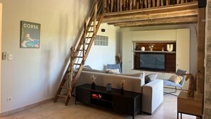 Ein Wohnzimmer mit Schlafgalerie, einer Couch, einem Couchtisch, einem Fernseher und einer Leiter.