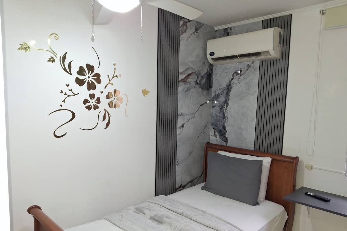 Quarto com cama, ar-condicionado fixado na parede e um adesivo decorativo.