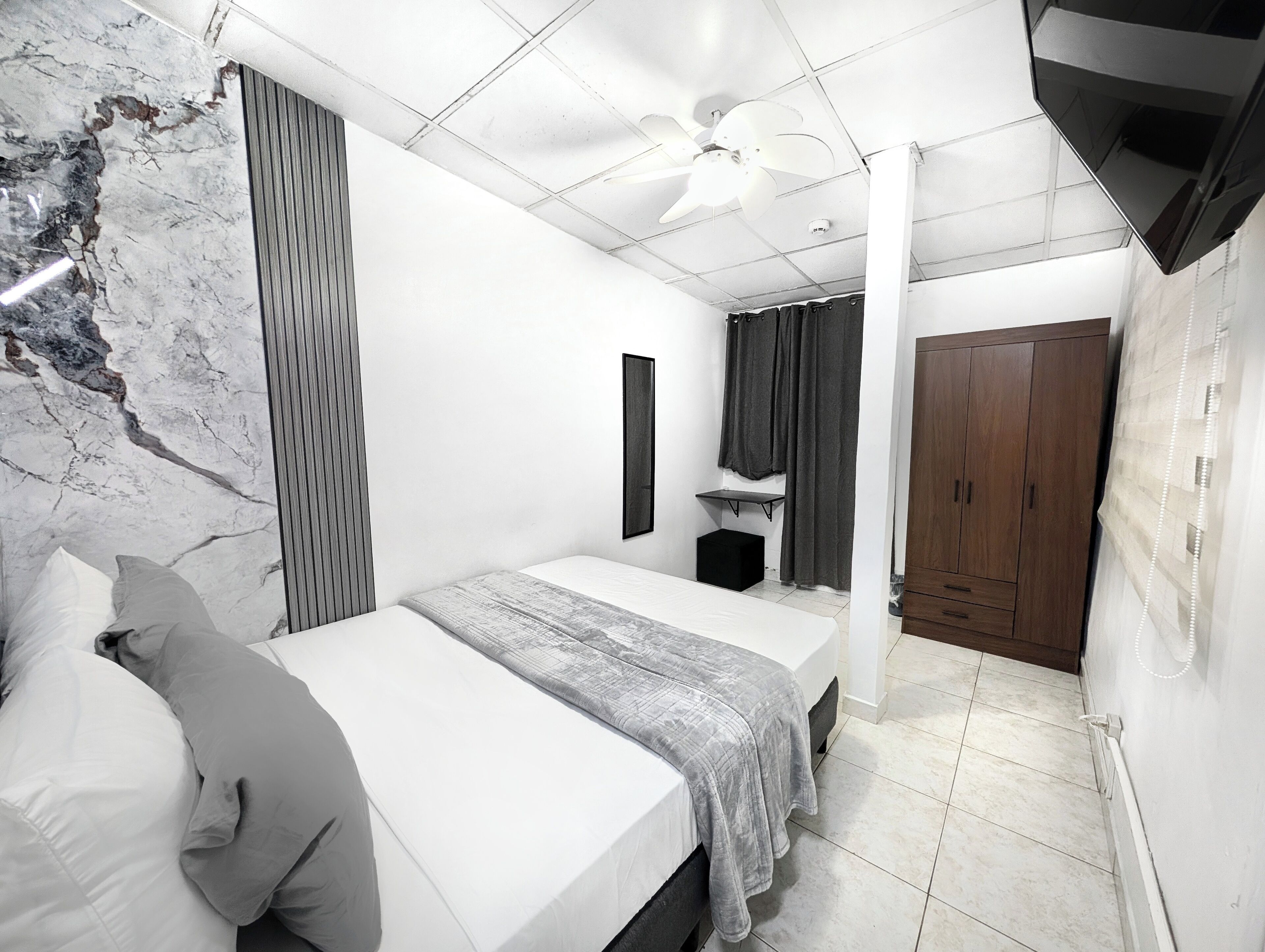 A modern bedroom with a bed, bedside table, and a wardrobe.