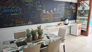 A dining area with a chalkboard menu, a table with a floral tablecloth, and chairs. - Hostal Yoha (Panama City)