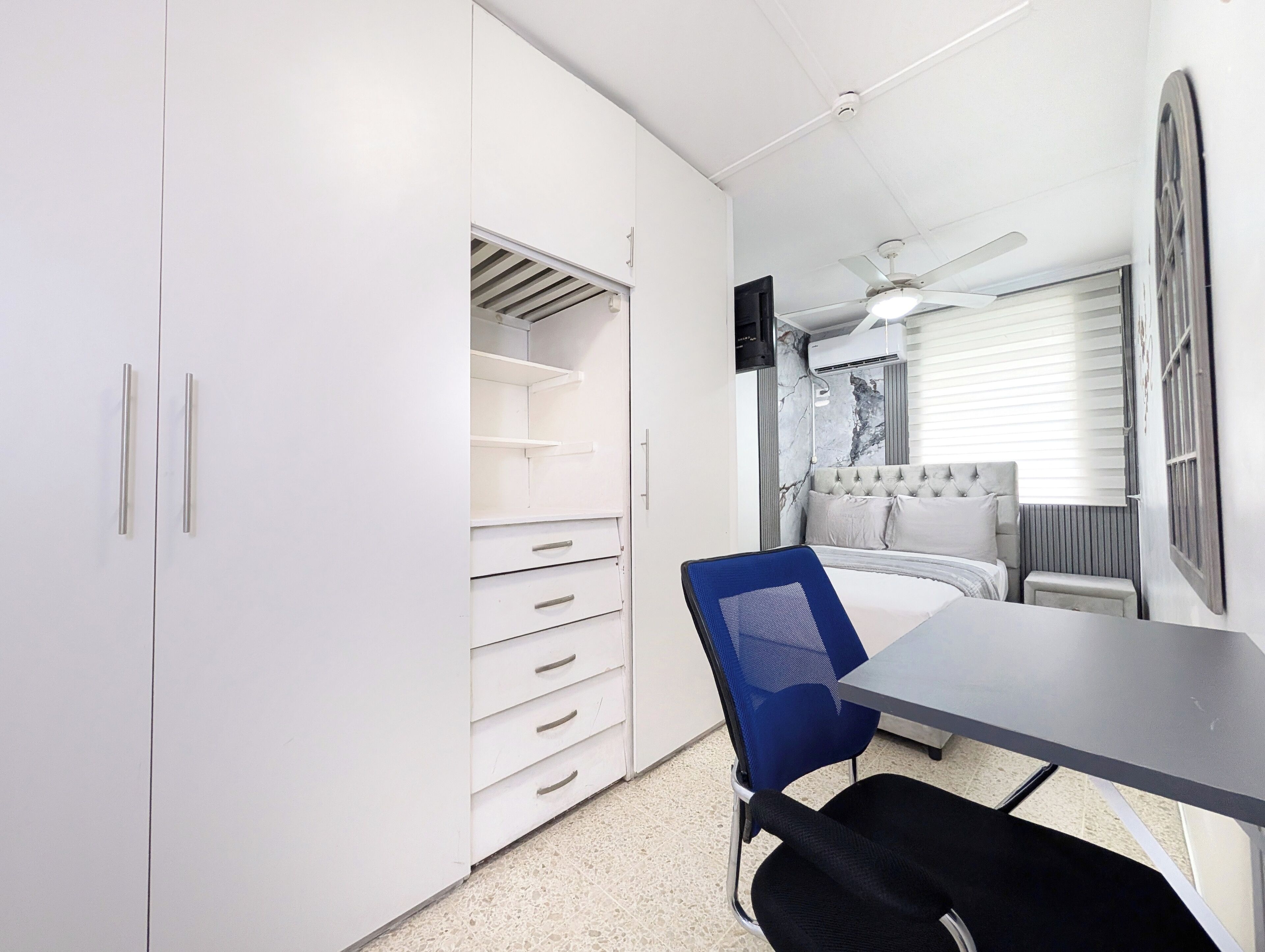 A bedroom with a bed, a desk, a chair, and a wardrobe.