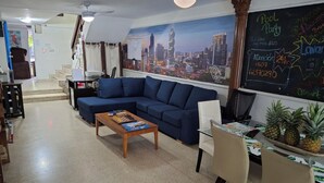 A hotel lobby with a blue sofa, a wooden coffee table, and a chalkboard with event details. - Hostal Yoha (Panama City)