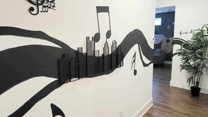 A hallway with a wall mural featuring abstract musical notes and cityscape designs. - East Nashville Luxury Condo~Rooftop Deck~Game Room~King Suite~Walk-In Showers (Nashville)