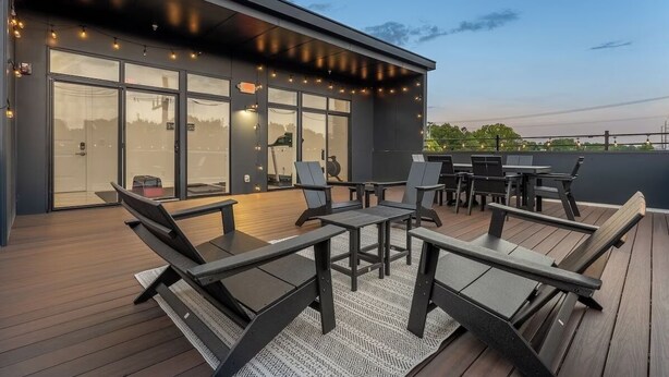 An outdoor deck with modern furniture and string lights. - East Nashville Luxury Condo~Rooftop Deck~Game Room~King Suite~Walk-In Showers (Nashville)