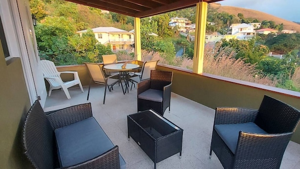 Un espacio al aire libre cubierto con mobiliario de mimbre, una mesa y sillas.