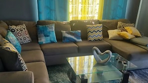 Una sala de estar moderna con un sofá modular, una mesa de centro de vidrio y una alfombra estampada.
