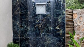 Un mur en marbre noir agrémenté de deux éléments décoratifs à eau et d’un carré encadré.